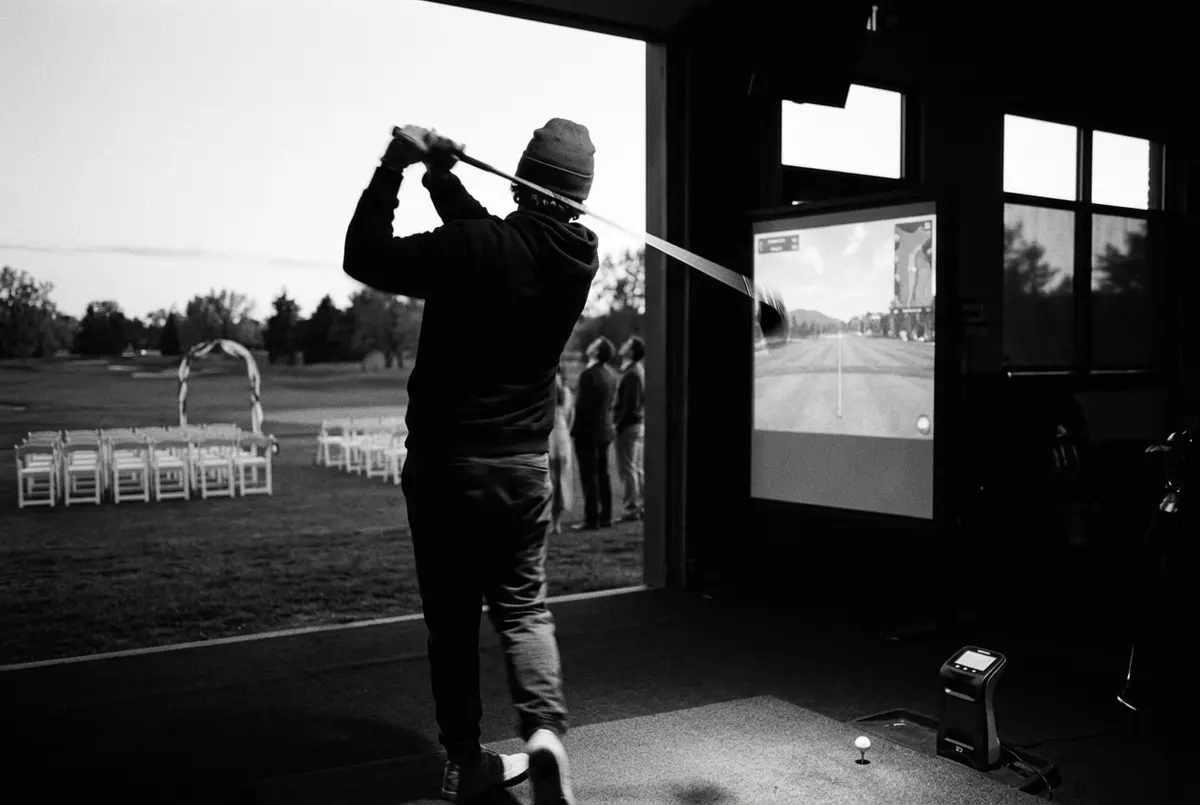 Golfer slaat af terwijl op de achtergrond stoelen en een boog voor een bruiloftsceremonie klaarstaan