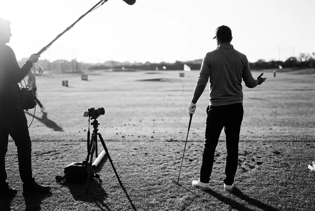 Golfer op de driving range gefilmd door een camera op een statief, van achteren gezien