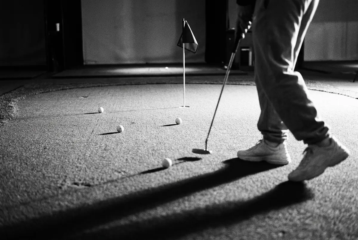 Drie golfballen op verschillende afstanden van de vlag op een green, met een speler vaag op de achtergrond.