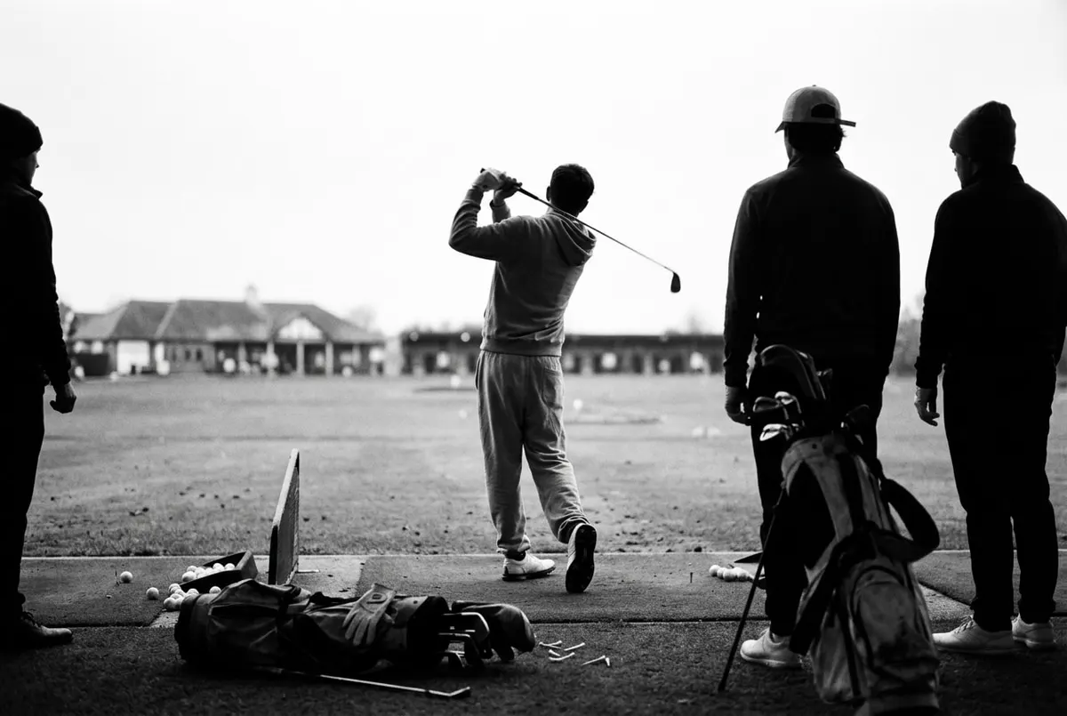 Groep beginners oefent de golfswing tijdens een gratis kennismakingsles op de driving range