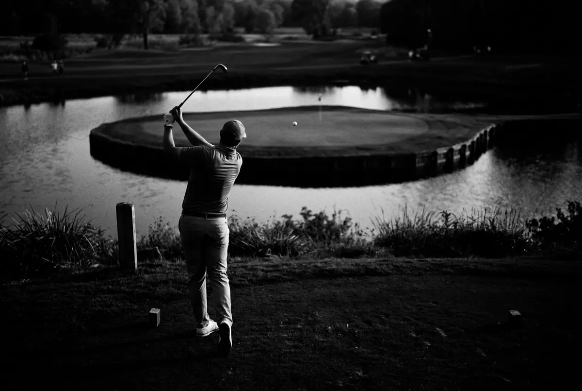 Golfer slaat vanaf de tee een bal richting een eilandgreen omringd door water