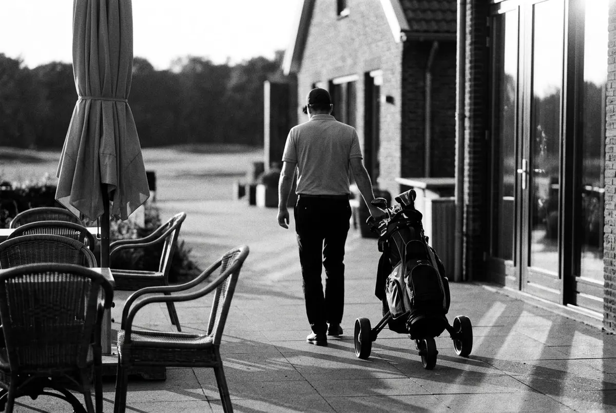 Golfer loopt met een trolley over een clubterras bij een Nederlandse golfbaan